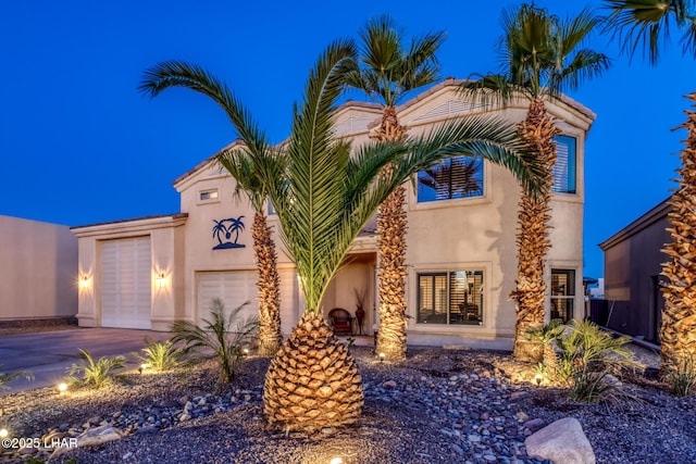 mediterranean / spanish home featuring a garage, driveway, and stucco siding