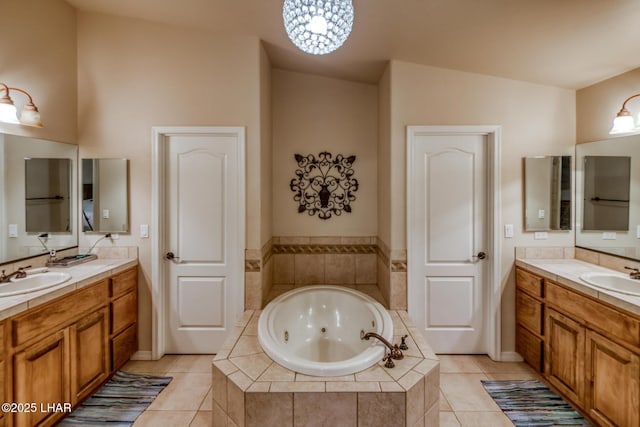 bathroom with tile patterned floors, a jetted tub, two vanities, and a sink