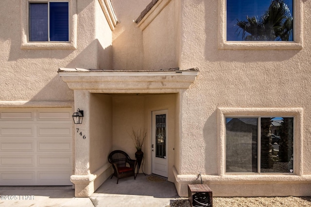 property entrance with stucco siding and a garage