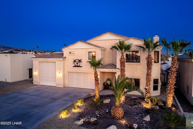 view of front facade featuring a chimney, stucco siding, concrete driveway, and fence