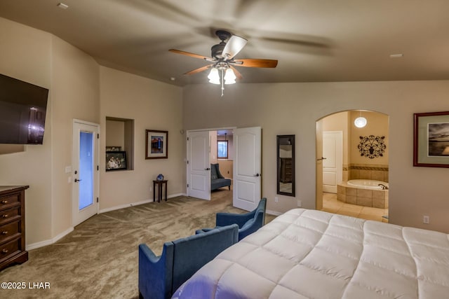 carpeted bedroom with baseboards, arched walkways, ensuite bath, and a ceiling fan