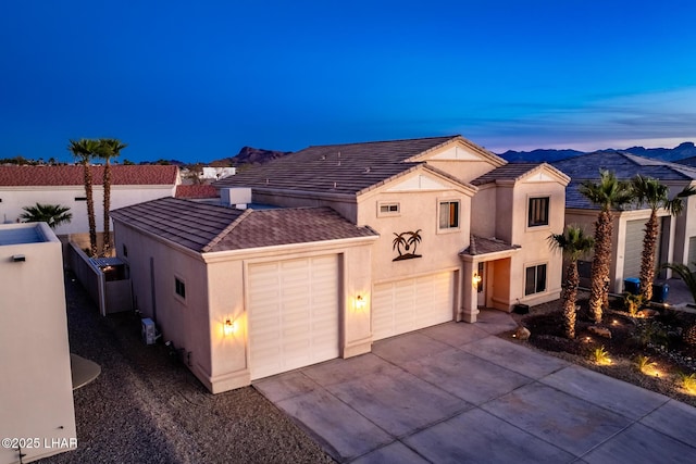 mediterranean / spanish-style home featuring an attached garage, fence, driveway, and stucco siding