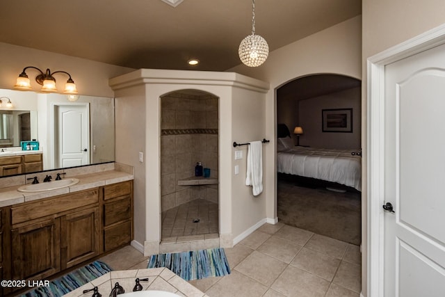 full bathroom featuring vanity, tile patterned floors, baseboards, and tiled shower