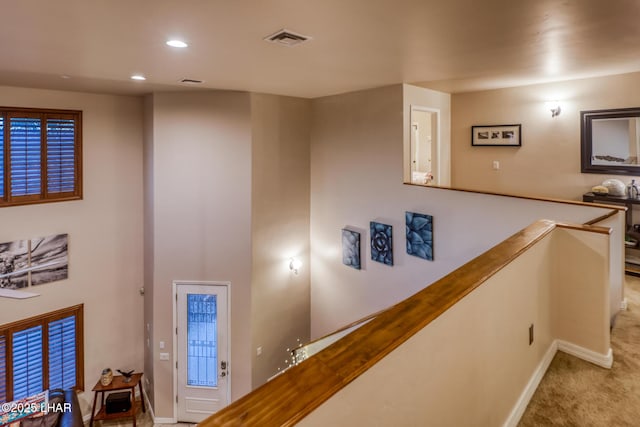 hall featuring visible vents, baseboards, carpet, an upstairs landing, and recessed lighting