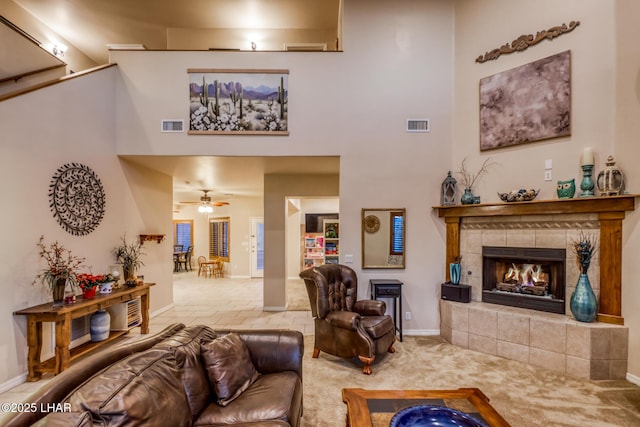 carpeted living area featuring a fireplace, visible vents, and a towering ceiling