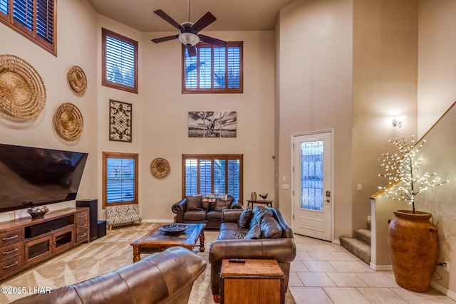 living room featuring stairway, a high ceiling, a healthy amount of sunlight, and ceiling fan