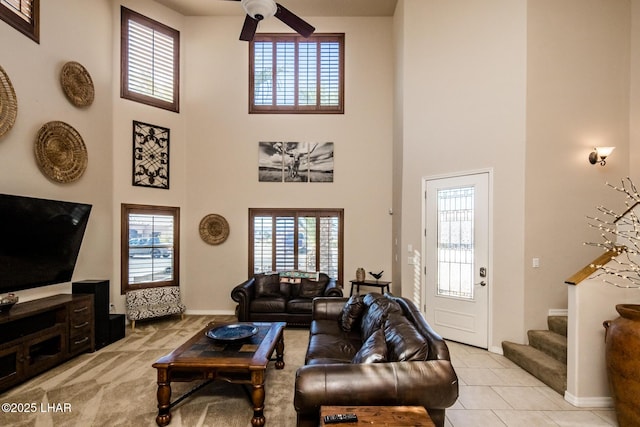 living area featuring stairway, a high ceiling, a healthy amount of sunlight, and ceiling fan