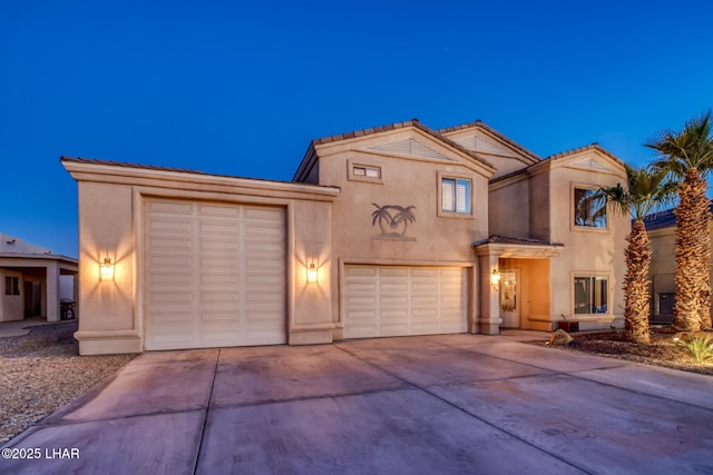 view of front of home featuring stucco siding, a tiled roof, and concrete driveway