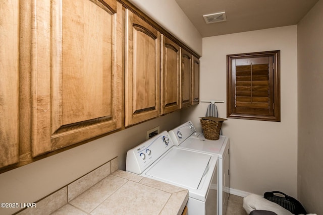 clothes washing area featuring visible vents, cabinet space, baseboards, and washing machine and dryer