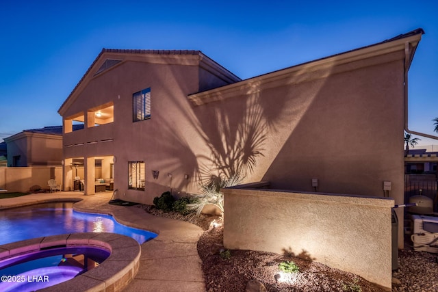 back of house featuring a fenced in pool, fence, stucco siding, an in ground hot tub, and a patio