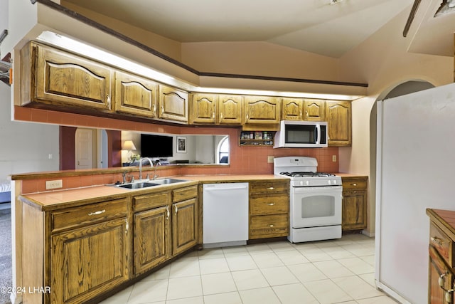 kitchen featuring sink, white appliances, tasteful backsplash, vaulted ceiling, and kitchen peninsula