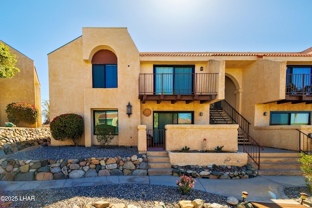 view of front of home with stairway, a balcony, a gate, and stucco siding