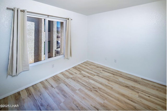 empty room featuring baseboards, a healthy amount of sunlight, and wood finished floors