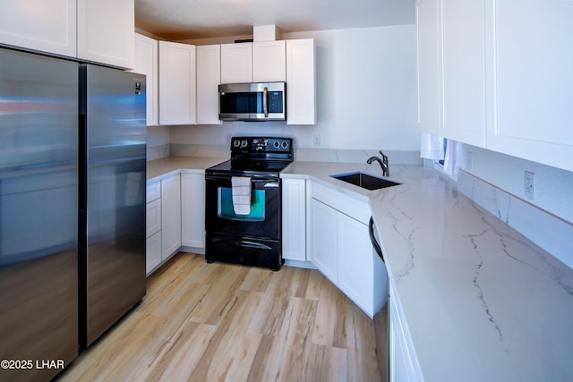 kitchen with a sink, white cabinets, light stone countertops, and stainless steel appliances