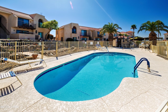 community pool featuring a patio area, fence, and a residential view