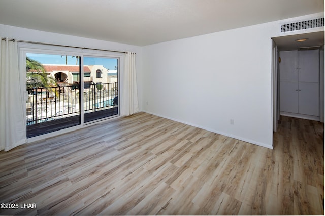 empty room featuring visible vents, baseboards, and wood finished floors