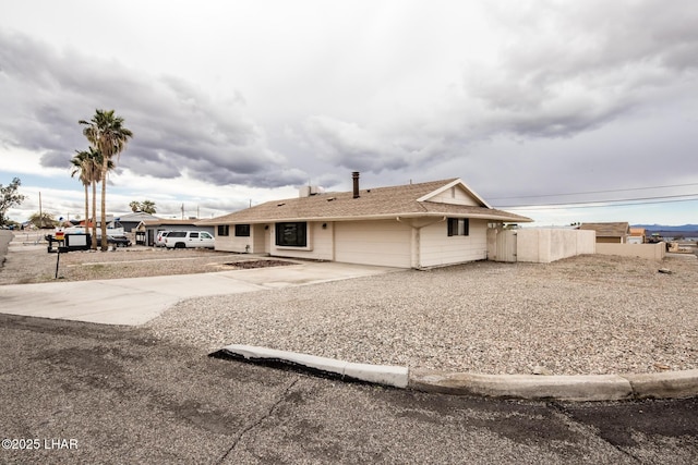 back of property with driveway, an attached garage, and fence