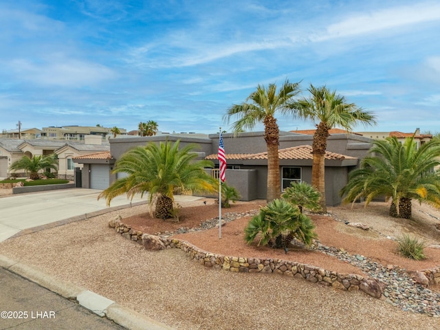 view of front of property with concrete driveway, a tiled roof, and stucco siding