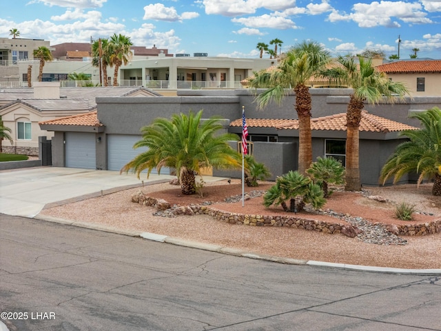 view of front of house with a tiled roof, an attached garage, driveway, and stucco siding