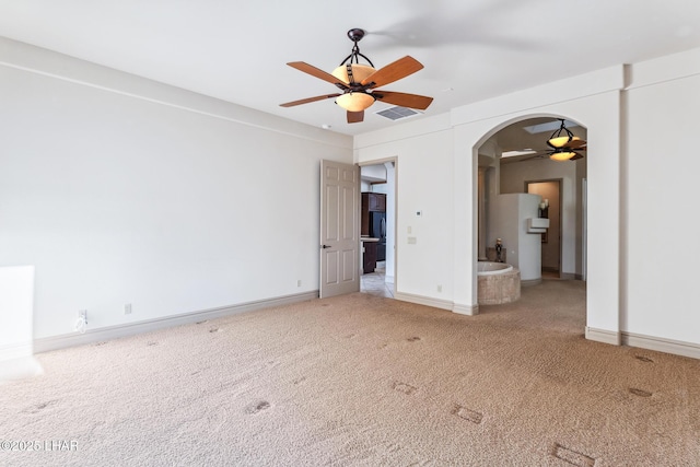 unfurnished room featuring ceiling fan, arched walkways, carpet, baseboards, and visible vents