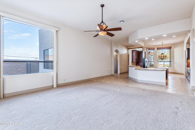 unfurnished living room with light carpet, arched walkways, visible vents, recessed lighting, and ceiling fan