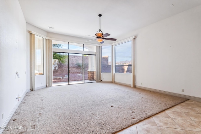 empty room featuring light tile patterned flooring, light carpet, baseboards, and ceiling fan