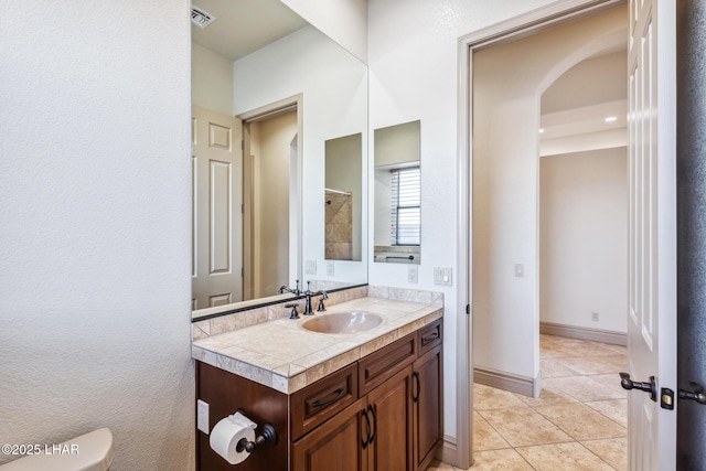 bathroom featuring tile patterned floors, toilet, visible vents, walk in shower, and vanity