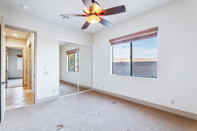 unfurnished bedroom with visible vents, a ceiling fan, a closet, baseboards, and light colored carpet
