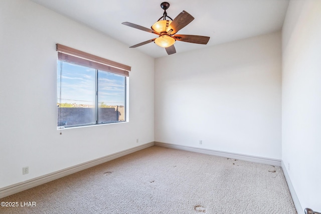 carpeted spare room featuring baseboards and a ceiling fan