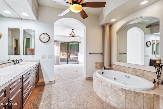 full bath featuring a tub with jets, a ceiling fan, a sink, and double vanity