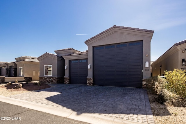 view of front facade featuring stone siding, an attached garage, a tiled roof, and stucco siding