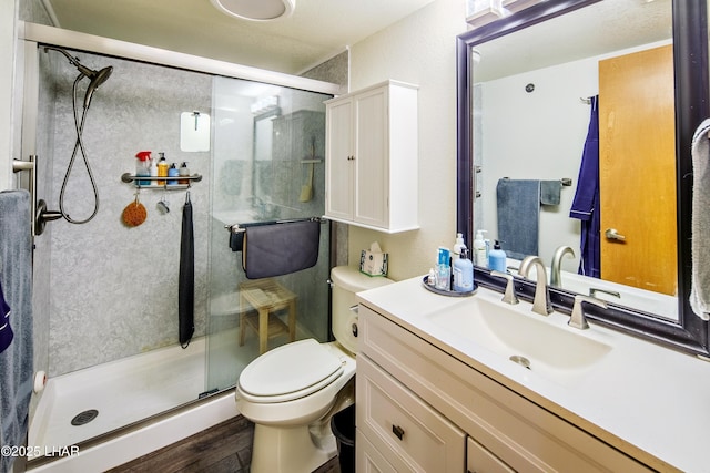 bathroom with vanity, a shower with shower door, wood-type flooring, and toilet