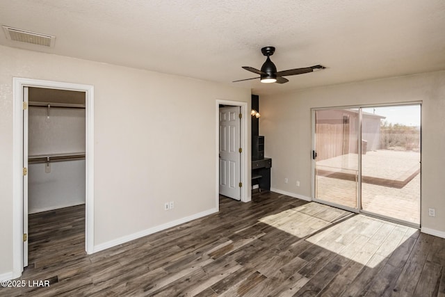 unfurnished bedroom with dark hardwood / wood-style floors, a walk in closet, access to exterior, and a textured ceiling