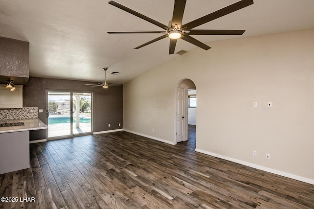 unfurnished living room featuring dark wood-type flooring, ceiling fan, and vaulted ceiling