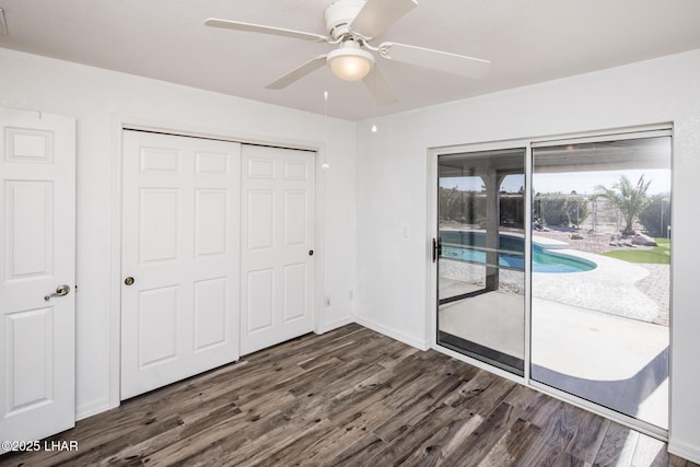 unfurnished bedroom featuring dark wood-type flooring, access to outside, ceiling fan, and a closet