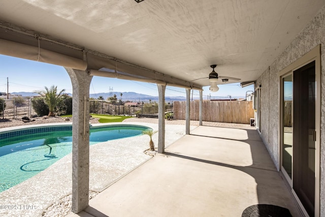 view of swimming pool featuring ceiling fan, a mountain view, and a patio