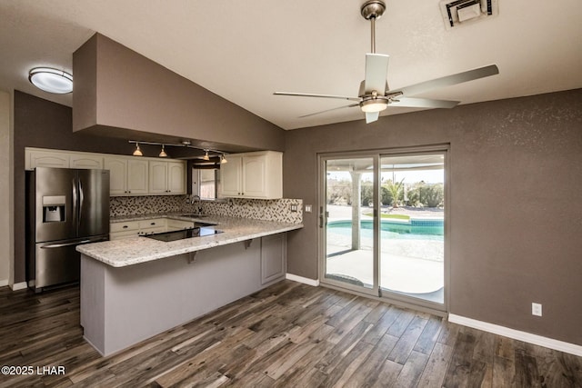 kitchen with a breakfast bar, white cabinetry, kitchen peninsula, stainless steel refrigerator with ice dispenser, and dark wood-type flooring