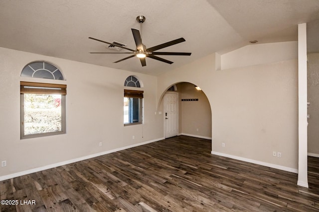 spare room featuring lofted ceiling, dark wood-type flooring, and a wealth of natural light