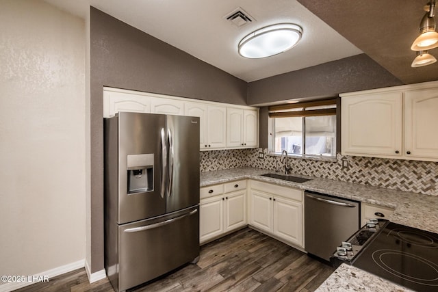 kitchen featuring lofted ceiling, sink, white cabinetry, stainless steel appliances, and light stone countertops