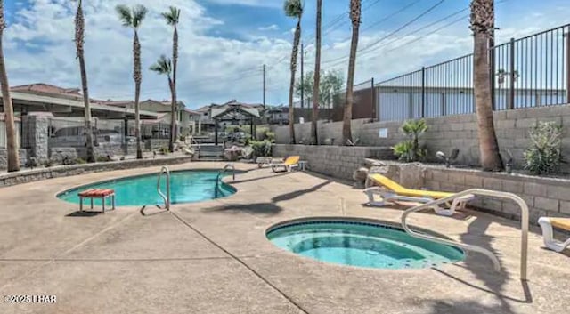 community pool with a patio area, fence, and a hot tub