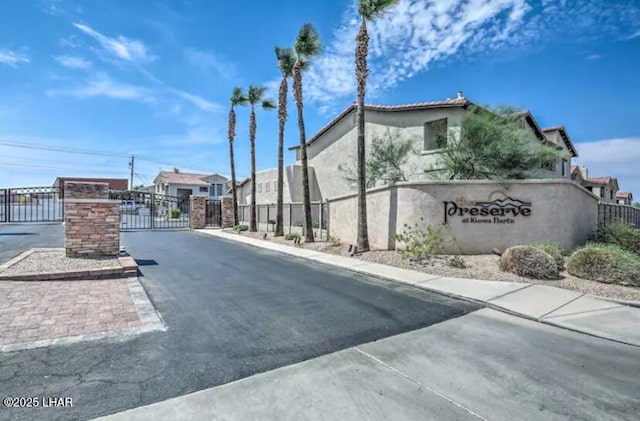 view of street featuring curbs, a gated entry, sidewalks, a gate, and a residential view