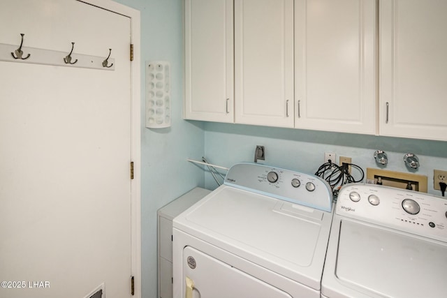 laundry room featuring separate washer and dryer and cabinets