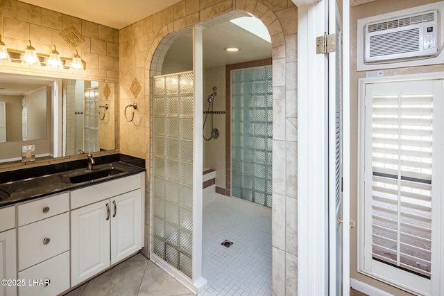 bathroom with an AC wall unit, vanity, tile patterned flooring, and a tile shower