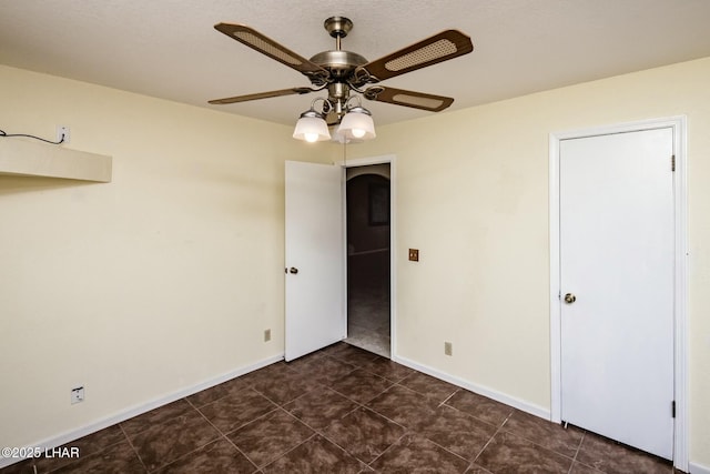 unfurnished bedroom with dark tile patterned flooring and ceiling fan