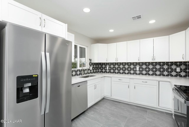 kitchen with stainless steel appliances, sink, decorative backsplash, and white cabinets