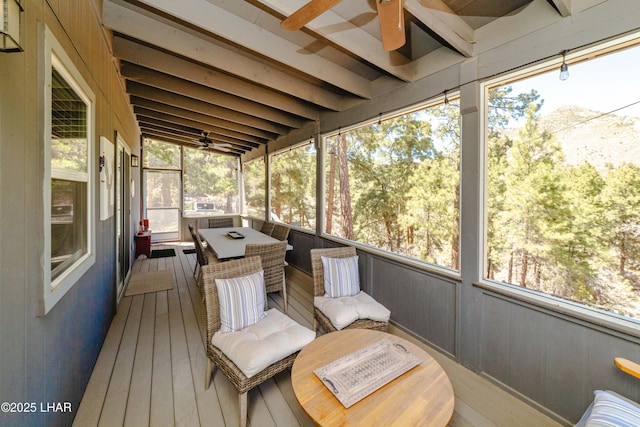 sunroom / solarium featuring a ceiling fan, beamed ceiling, and plenty of natural light