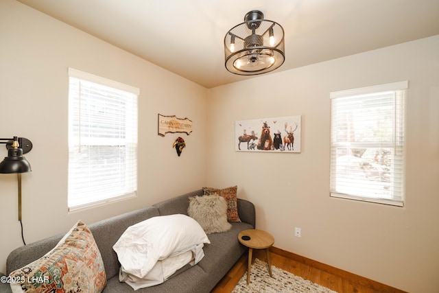 living area featuring baseboards, wood finished floors, and a notable chandelier