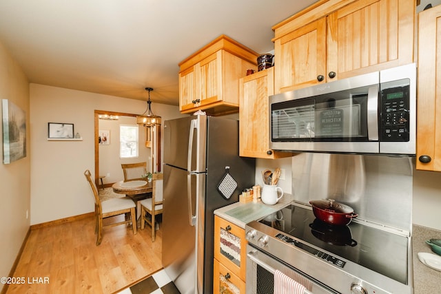 kitchen featuring light wood-style floors, light brown cabinets, stainless steel appliances, and a chandelier