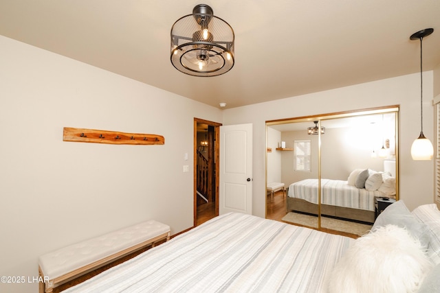bedroom with a chandelier, wood finished floors, and a closet