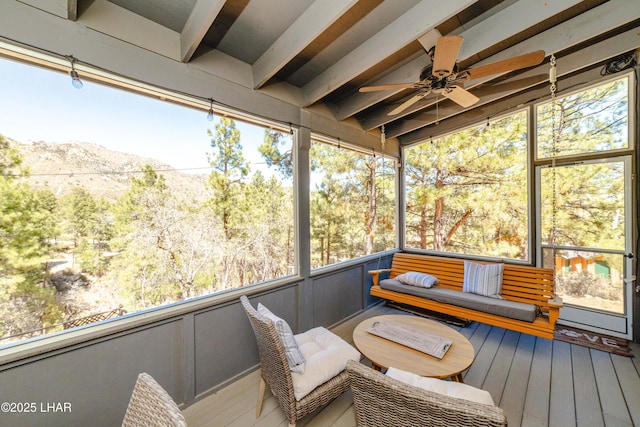sunroom with a ceiling fan, a mountain view, and beam ceiling